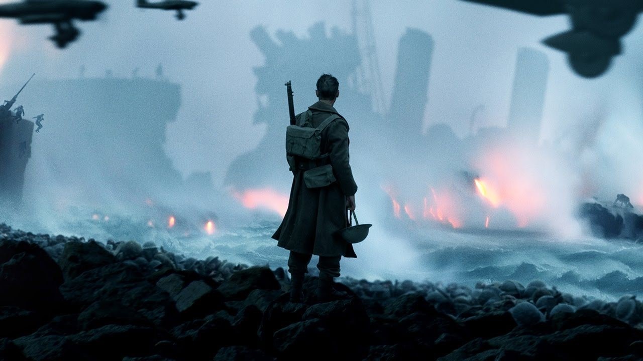 Från filmen Dunkirk. En soldat står på stranden och tittar ut över en söndersprängt fartyg till havs. 