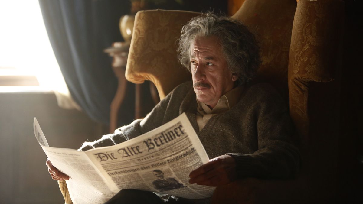 Geoffrey Rush som Albert Einstein i "Genius". Han sitter i en fåtölj och läser tidningen. 