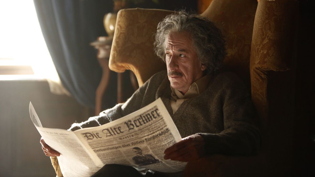 Geoffrey Rush som Albert Einstein i "Genius". Han sitter i en fåtölj och läser tidningen.