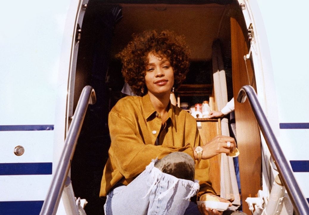 Whitney Houston framför ingången till ett flygplan.