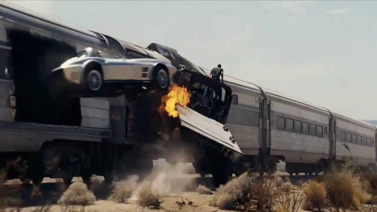 Ett ökenfordon sitter fast i ett tåg medan en bil hoppar från samma tåg i Fast Five.