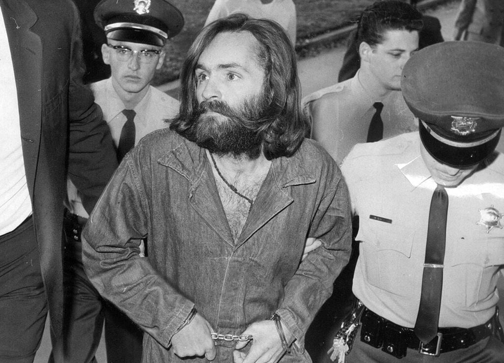 Charles Manson blir eskorterad av polis vid häktning. Viaplayserien Manson's Bloodline berättar om sektledarens påverkan på familj och vänner.