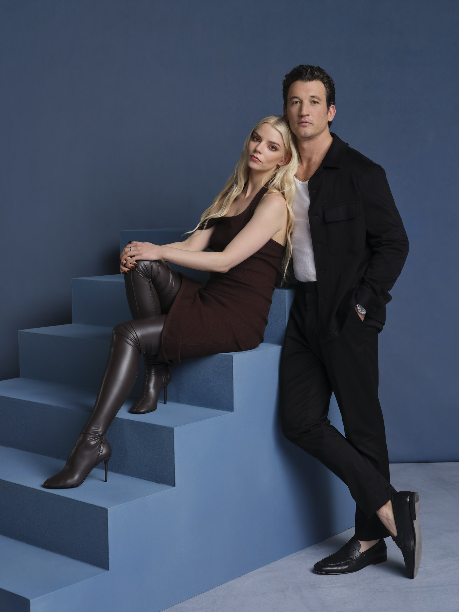 Anya Taylor-Joy och Miles Teller poserar jämte varandra vid en blå trappa.